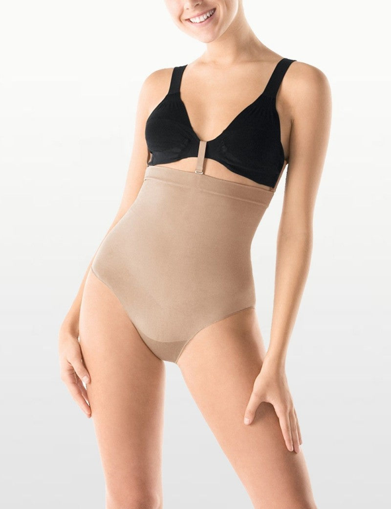 Woman wearing a black bra and beige shapewear on a white background