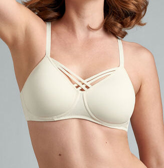 A woman wearing a beige padded mastectomy bra with X-shaped front closures.
