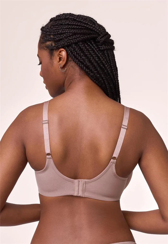 Woman wearing a beige bra against a plain background