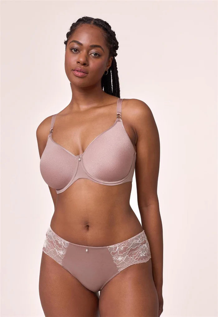 Woman wearing a beige bra and panties set against a plain background