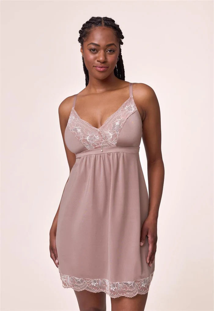 Woman wearing a lace-trimmed nightgown against a plain background