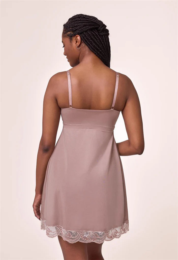 Woman wearing a beige slip dress with lace trim on a plain background