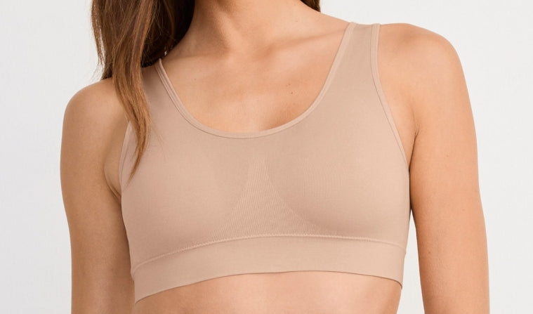 Beige sports bra worn by a person on a plain background