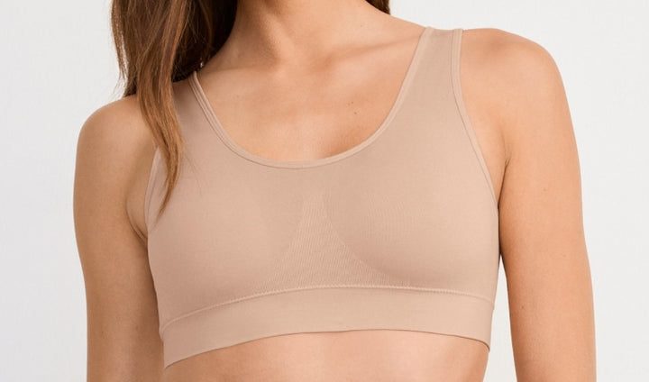 Beige sports bra worn by a person on a plain background