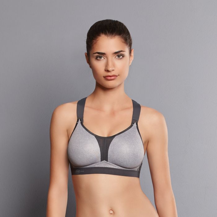 Woman wearing a gray and black bra against a gray background