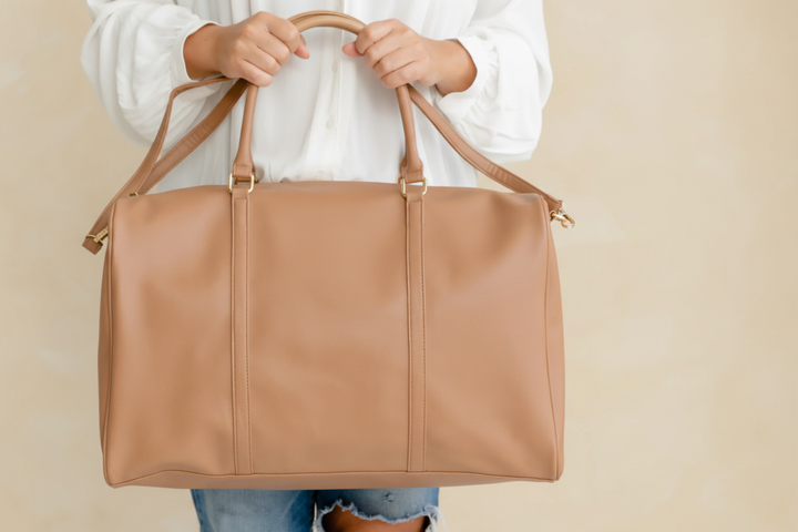 Person holding a tan duffel bag 