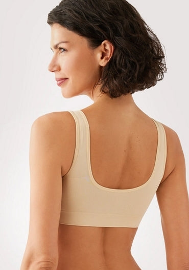 Woman wearing a beige sports bra on a plain background