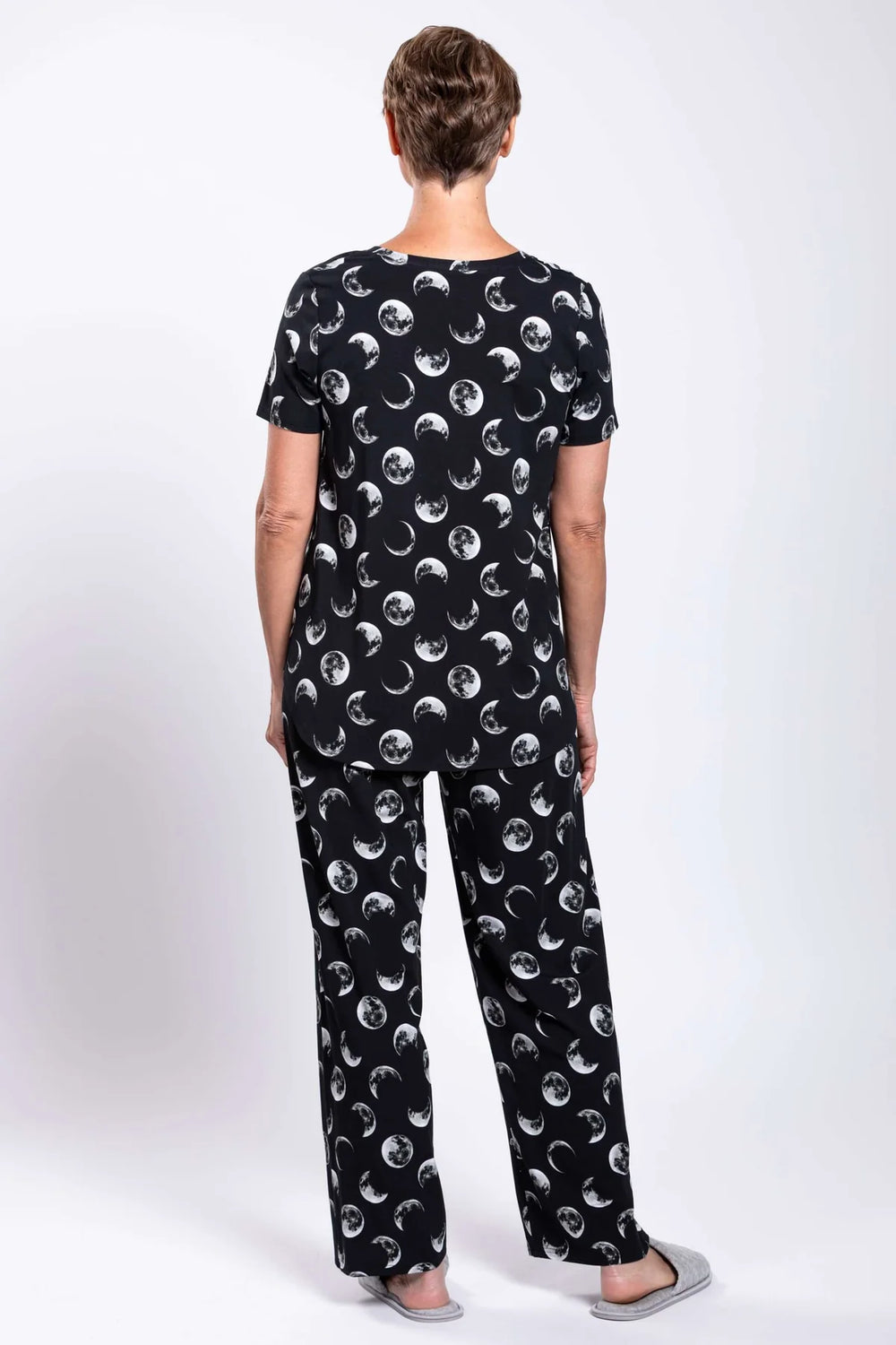 Person wearing a black outfit with moon phase pattern on a white background