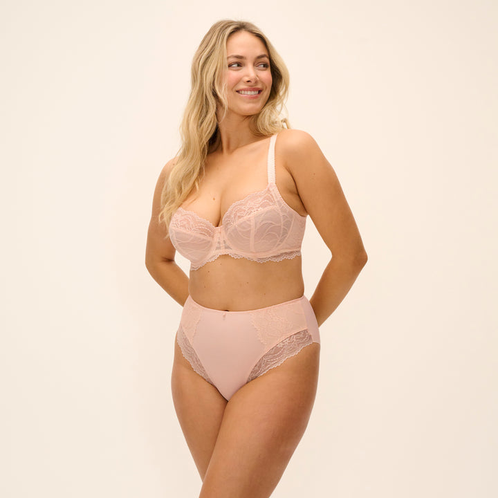 Woman wearing a matching bra and panties set on a beige background