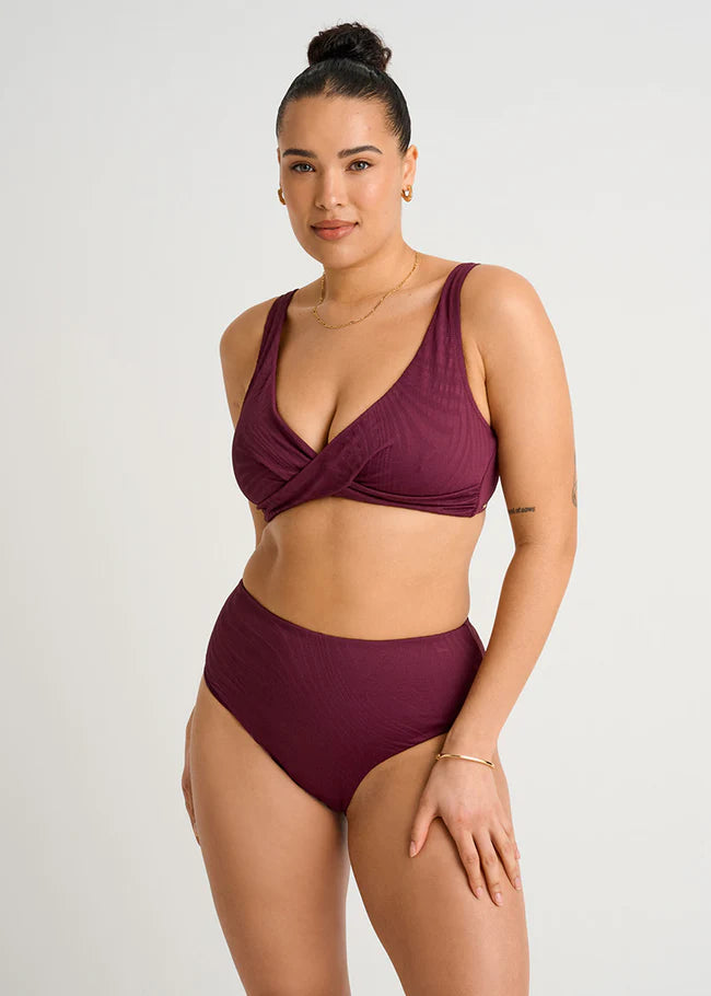 Woman wearing a burgundy bikini set on a plain background