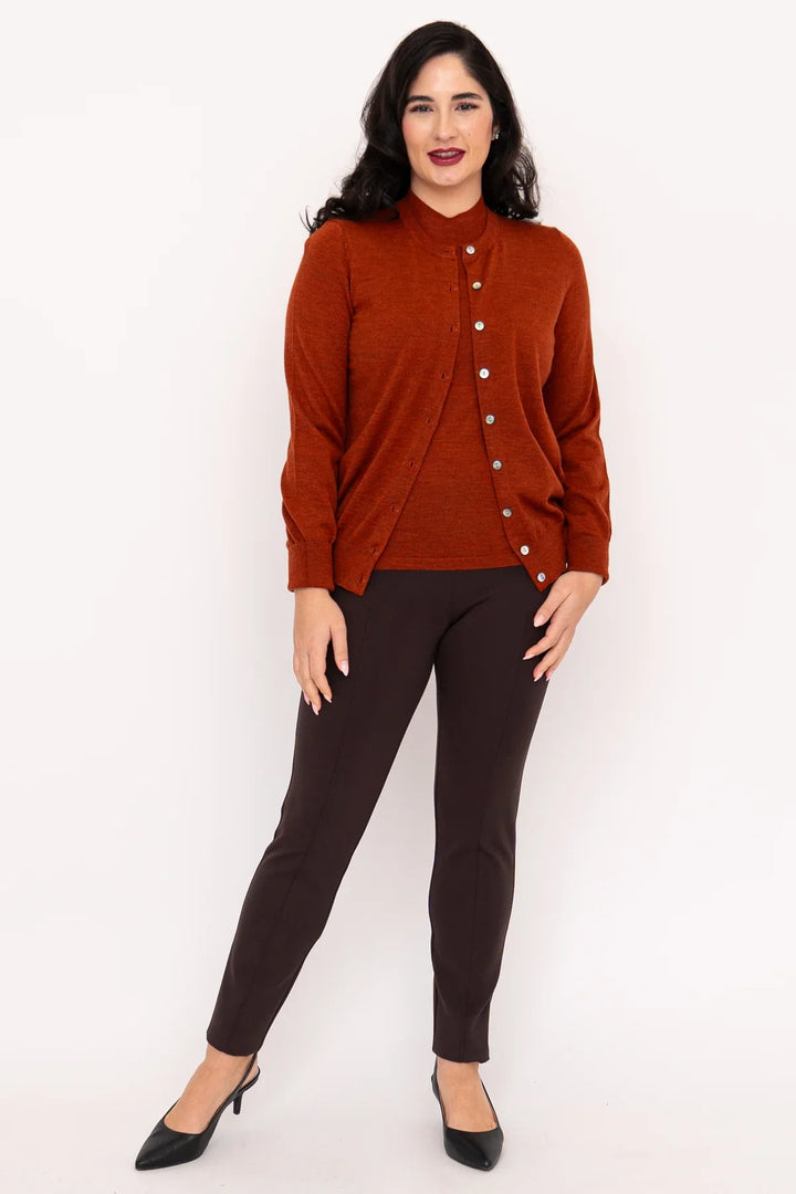 Woman wearing a rust-colored cardigan and black pants on a white background