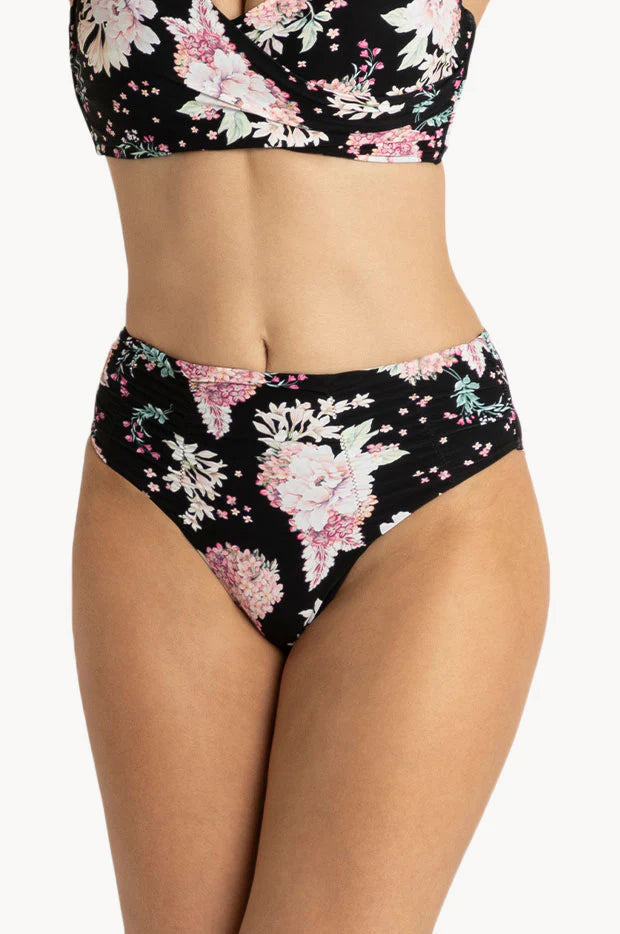 A pair of mid-rise swim bottoms with a floral design in black, pink, and white colors, featuring ruching details and a seamless waist.