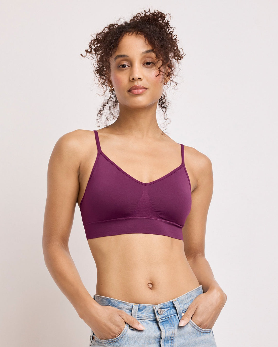 Woman wearing a purple bralette against a plain background
