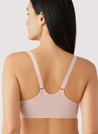 Woman wearing a beige bralette on a plain background