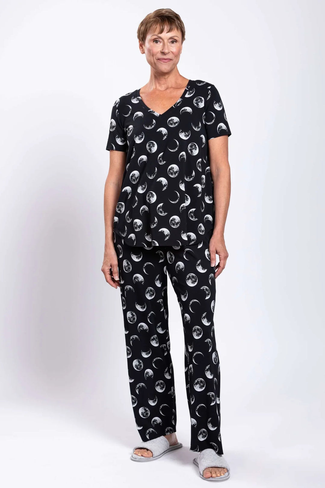 Woman wearing a black pajama set with moon phases on a white background
