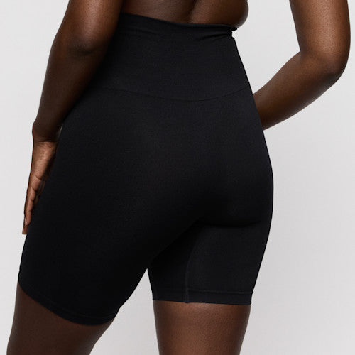 Black high-waisted shorts worn by a person on a light gray background