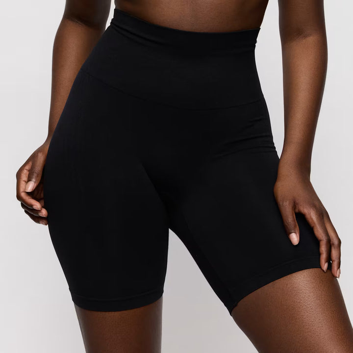 Person wearing black high-waisted shorts on a plain background