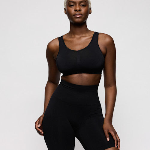 Person wearing a black sports bra and leggings on a light gray background